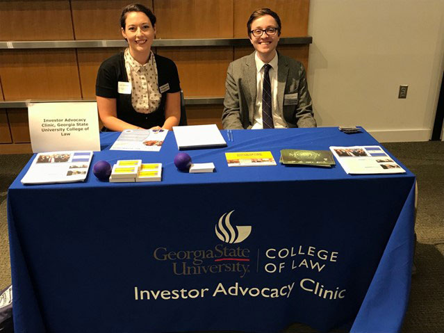 A male and female law student sitting at a desk covered with pamphlets.