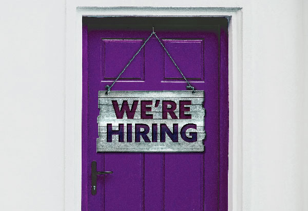 Purple wooden door with showing a 'We're Hiring' sign.